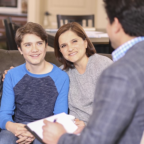 madre e figlio sorridenti a colloquio con uno psicologo