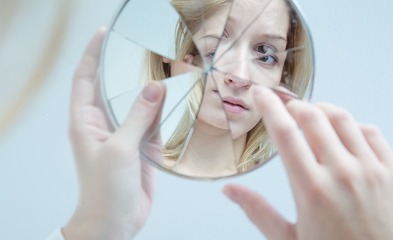 volto di donna riflesso in uno specchio rotto