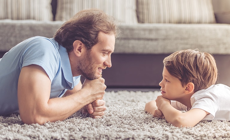 papà e figlio faccia a faccia sdraiati su un tappeto